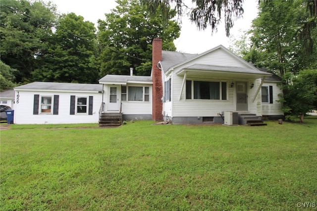 back of property featuring a chimney, central AC unit, and a yard