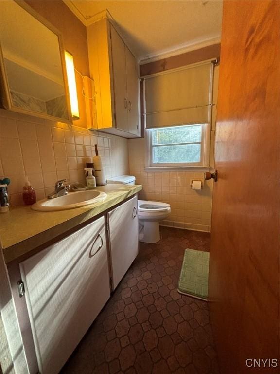 bathroom featuring toilet, vanity, and tile walls