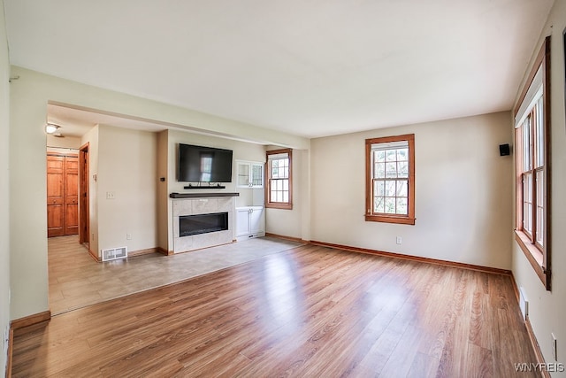 unfurnished living room featuring light wood-type flooring and a fireplace