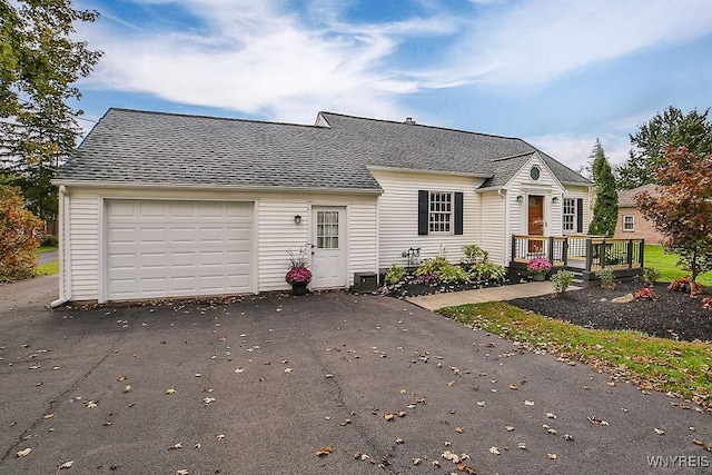 cape cod house featuring a deck, a garage, asphalt driveway, a shingled roof, and central AC