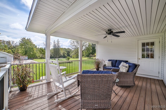 wooden terrace featuring a yard, an outdoor living space, and ceiling fan