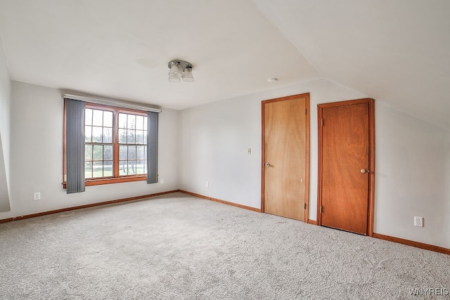 carpeted empty room with lofted ceiling