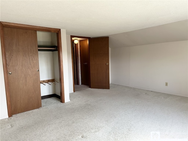 unfurnished bedroom with light colored carpet, a textured ceiling, and a closet