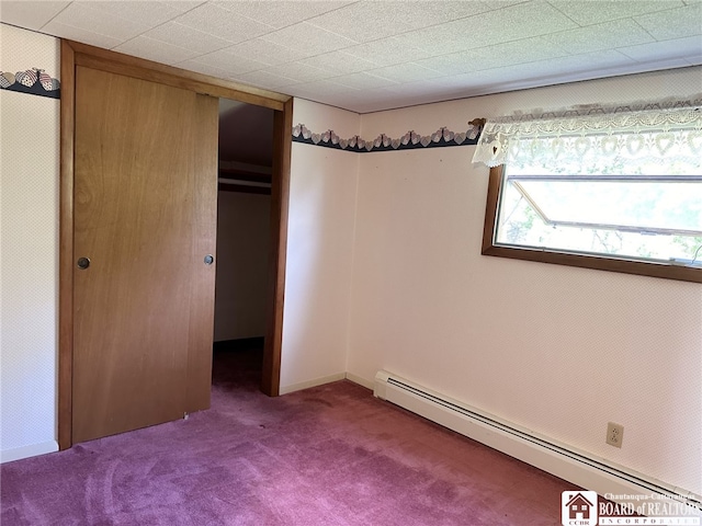 unfurnished bedroom featuring a baseboard radiator, dark colored carpet, and a closet