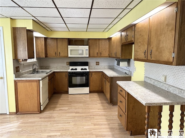 kitchen featuring sink, white appliances, light hardwood / wood-style flooring, backsplash, and a drop ceiling