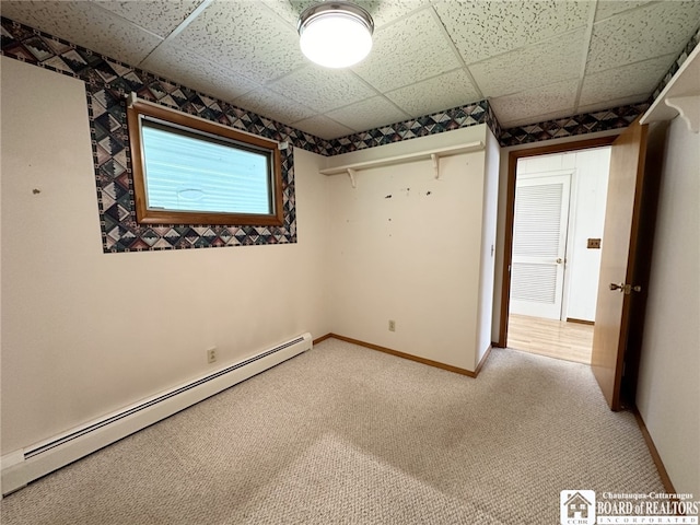 unfurnished bedroom featuring a baseboard radiator, a paneled ceiling, and carpet flooring