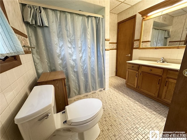 bathroom with walk in shower, tile walls, vanity, and toilet