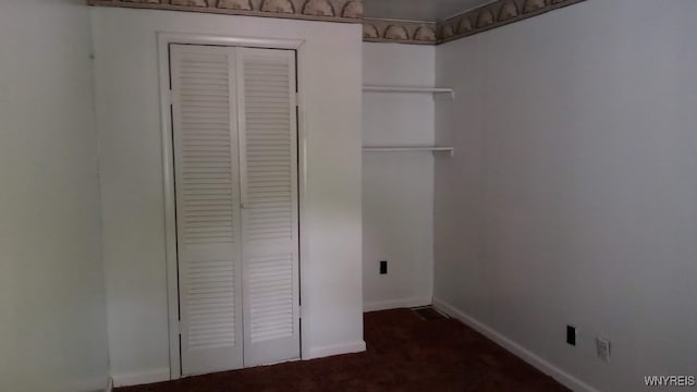 unfurnished bedroom featuring dark carpet and a closet