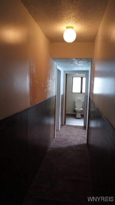 hall with a textured ceiling and carpet flooring