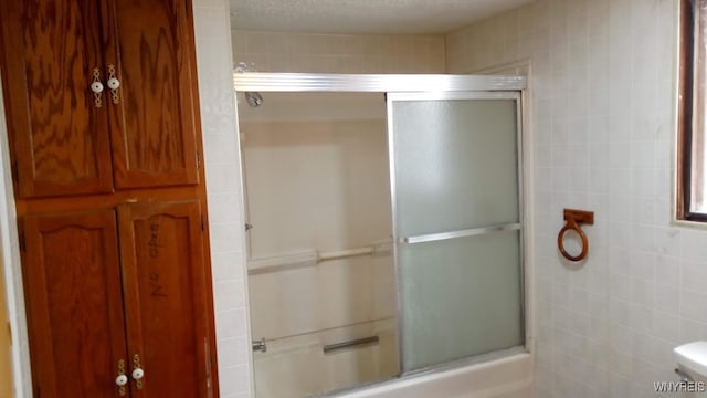 bathroom with enclosed tub / shower combo, a textured ceiling, tile walls, and toilet