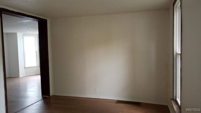 empty room with a textured ceiling and hardwood / wood-style flooring