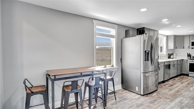 kitchen with gray cabinets, sink, stainless steel appliances, and light hardwood / wood-style floors