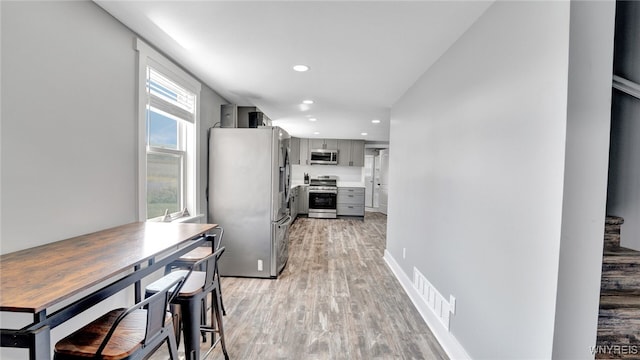 kitchen with light wood-type flooring, stainless steel appliances, and gray cabinets