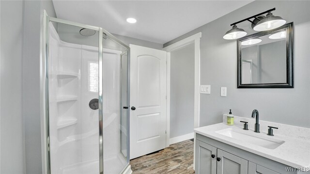 bathroom featuring vanity, wood-type flooring, and a shower with shower door