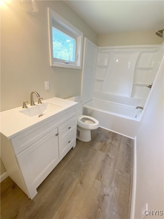 full bathroom with washtub / shower combination, vanity, toilet, and hardwood / wood-style flooring