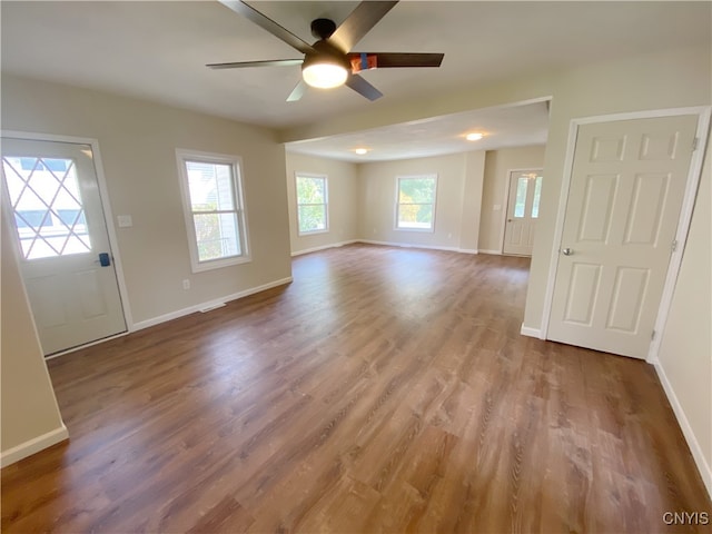 unfurnished living room with wood-type flooring, ceiling fan, and a wealth of natural light