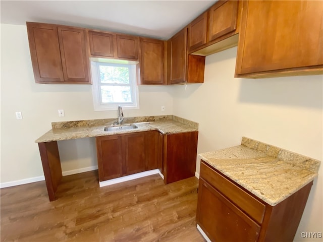 kitchen featuring light stone countertops, sink, and hardwood / wood-style flooring