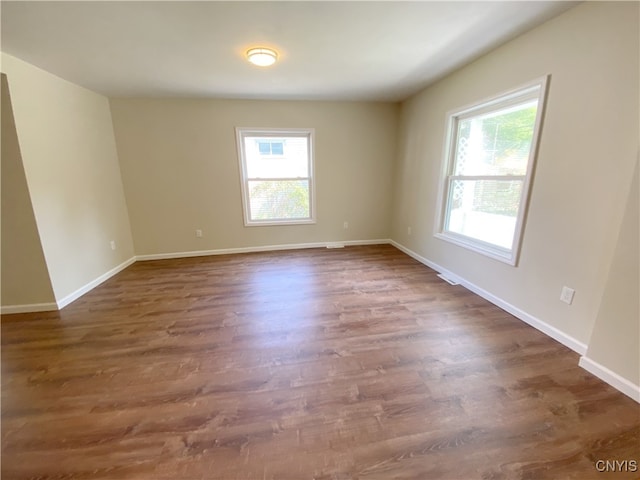 unfurnished room featuring a healthy amount of sunlight and dark hardwood / wood-style floors