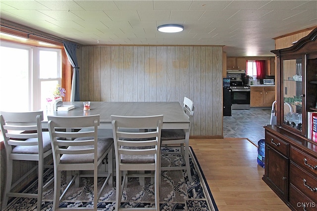 dining area featuring light wood-type flooring and wood walls