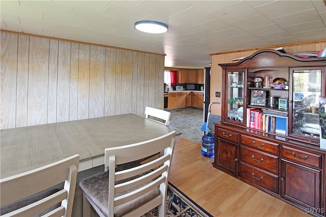 dining space featuring light wood-type flooring and wood walls