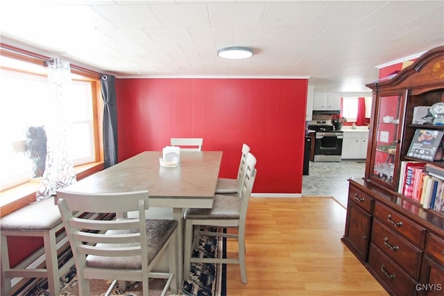 dining area featuring light wood-type flooring and crown molding