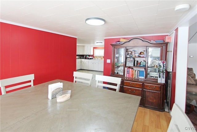 dining area with ornamental molding and light wood finished floors