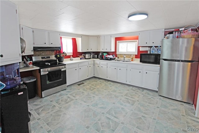 kitchen with white cabinets, appliances with stainless steel finishes, light countertops, under cabinet range hood, and a sink