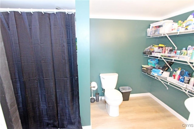 bathroom featuring curtained shower, wood finished floors, toilet, and baseboards