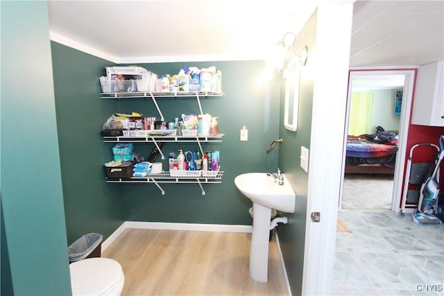 half bathroom featuring baseboards, toilet, and wood finished floors