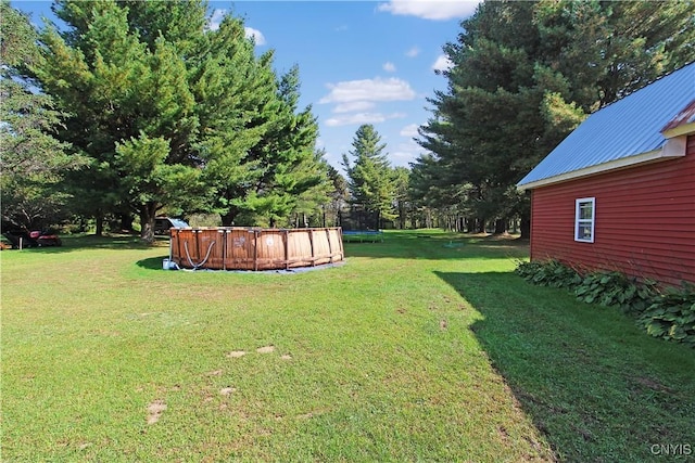 view of yard with a trampoline and an outdoor pool