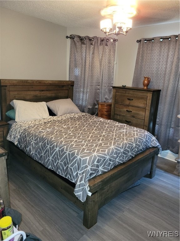 bedroom featuring a notable chandelier, hardwood / wood-style floors, and a textured ceiling