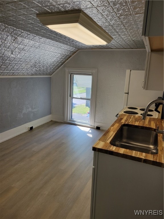 interior space featuring gray cabinets, lofted ceiling, hardwood / wood-style floors, sink, and wood counters