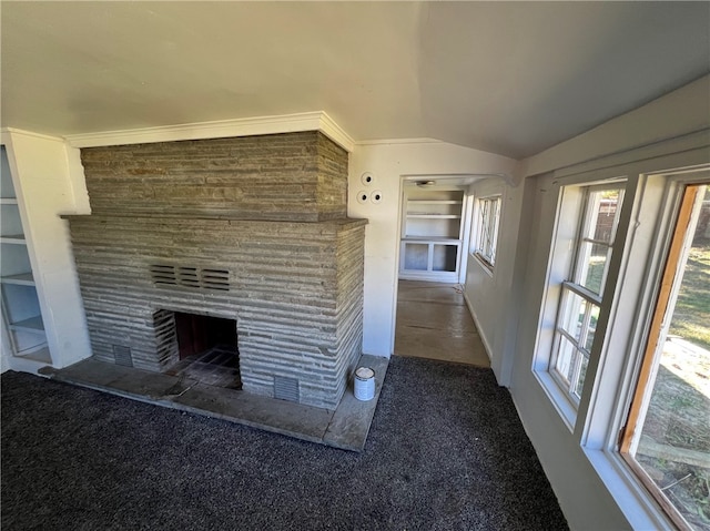 unfurnished living room featuring dark carpet, a fireplace, and vaulted ceiling