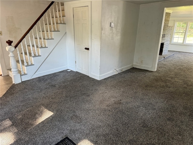 unfurnished living room featuring dark carpet and a brick fireplace