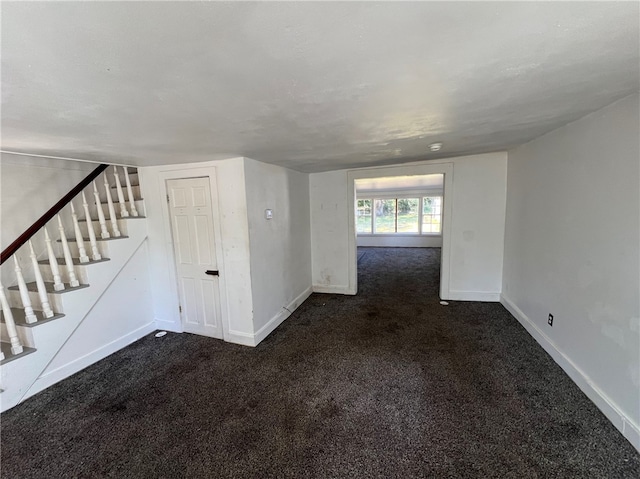 unfurnished living room with dark colored carpet and a textured ceiling