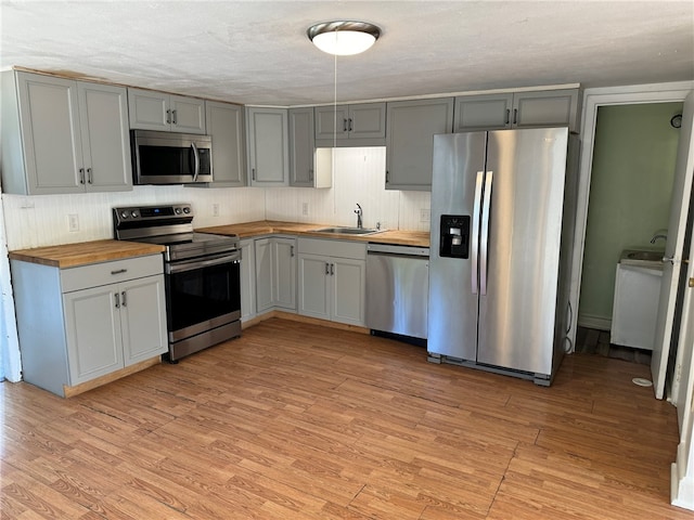 kitchen featuring stainless steel appliances, light wood-type flooring, and wooden counters