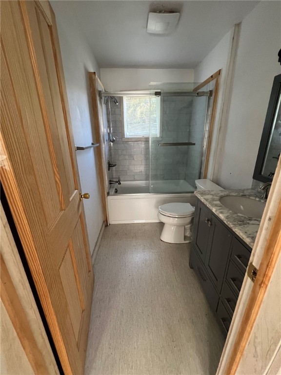 full bathroom with shower / bath combination with glass door, vanity, and toilet