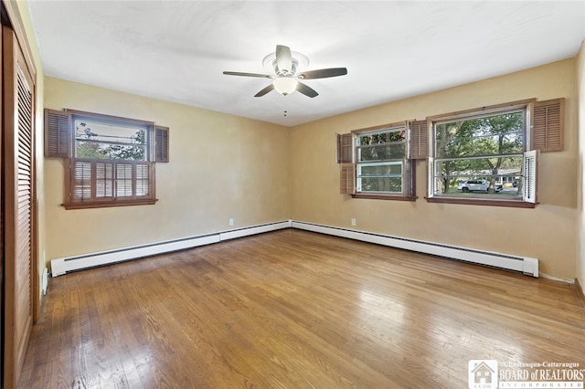 spare room with a baseboard heating unit, hardwood / wood-style floors, and ceiling fan