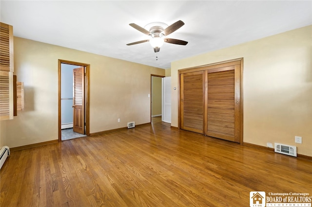 unfurnished bedroom featuring light wood-type flooring, ceiling fan, and baseboard heating