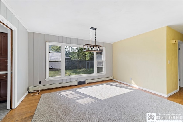 unfurnished dining area featuring ornamental molding, light wood-type flooring, a chandelier, and a baseboard heating unit