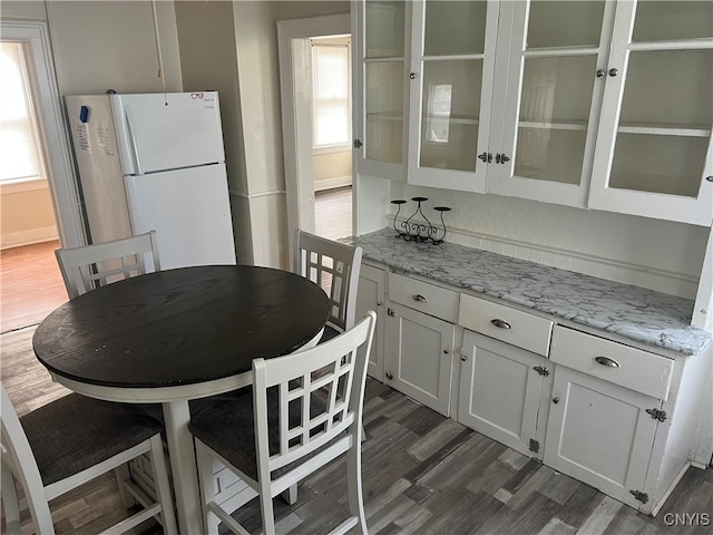 kitchen with light stone countertops, white cabinets, dark wood-type flooring, and white refrigerator