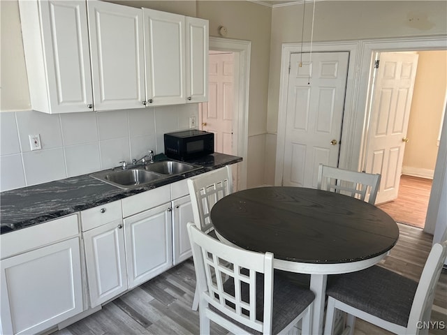 kitchen with tasteful backsplash, white cabinetry, sink, and light hardwood / wood-style floors