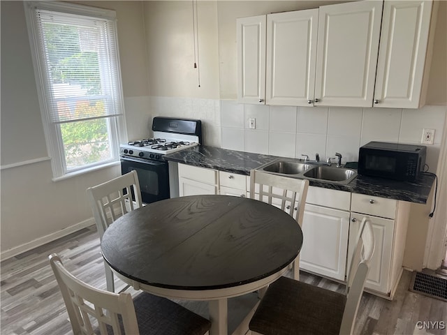 kitchen with white cabinets, tasteful backsplash, sink, white range with gas stovetop, and light hardwood / wood-style floors