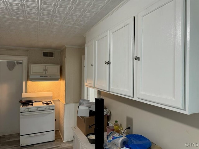 kitchen with white cabinets, light hardwood / wood-style floors, and gas range gas stove