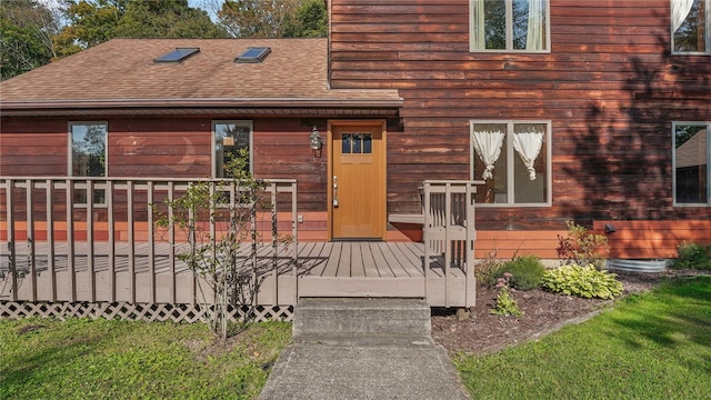 entrance to property with a wooden deck and a lawn