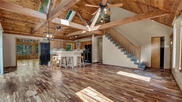 kitchen featuring a breakfast bar, beam ceiling, ceiling fan with notable chandelier, and dark hardwood / wood-style flooring