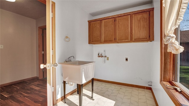 laundry room featuring cabinets, light hardwood / wood-style floors, hookup for an electric dryer, and plenty of natural light