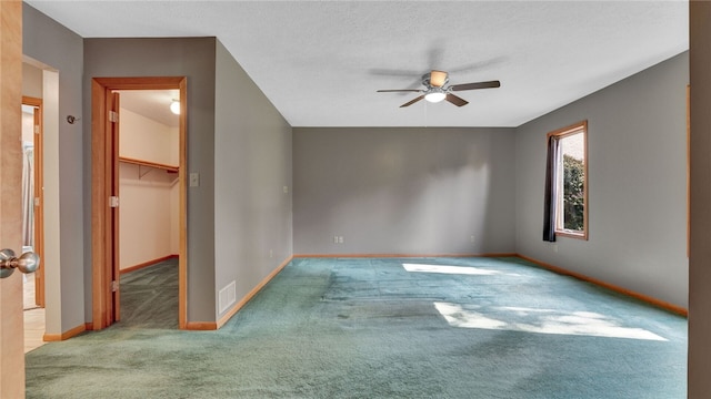 carpeted spare room with ceiling fan and a textured ceiling