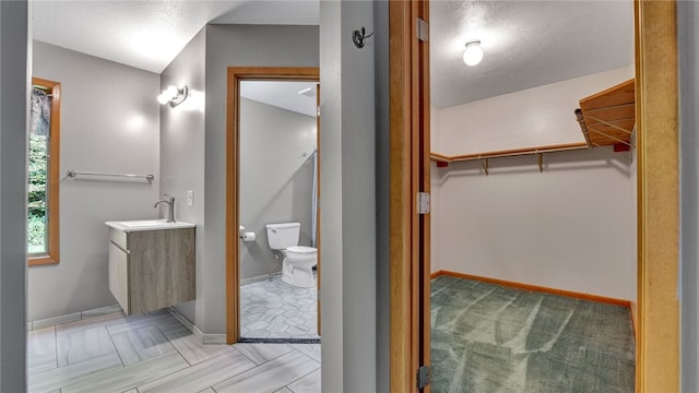 bathroom with a textured ceiling, vanity, and toilet