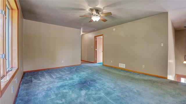 carpeted spare room featuring a textured ceiling and ceiling fan